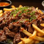 Thin Sliced Beef Recipes Your Whole Family Will Love 3 Plate of thin sliced beef topped with sesame seeds and sauce, served with crispy fries, rice, and dipping sauce.