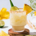 Coconut and Pineapple Mocktail Magic: A Guilt-Free Tropical Escape 5 Coconut and pineapple mocktail in a frosted glass, garnished with a pineapple wedge, lime slice, and toasted coconut flakes, on a wooden coaster with fresh fruit in the background, bright summer ambiance.