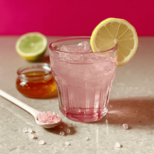 Pink salt recipe drink with ice, lemon slice garnish, honey and pink Himalayan salt